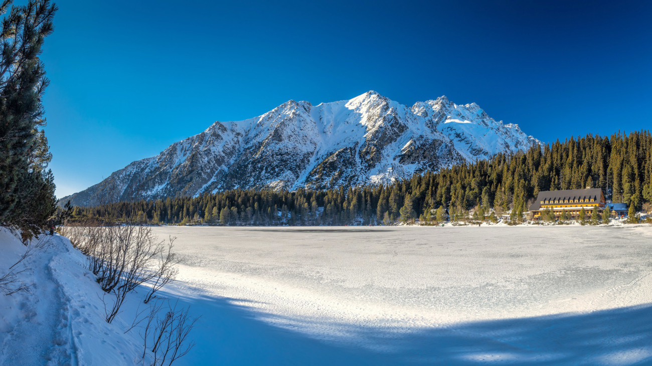 Panoramic view of mountain landscape with frozen tarn at winter season. The Popradske pleso lake in High Tatras National Park, Slovakia, Europe.