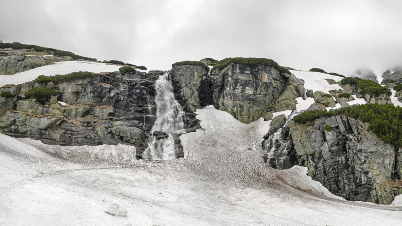 Waterfall 'Skok' in High Tatras, Slovakia, during overcast spring day, dirty snow still covering most of ground.
