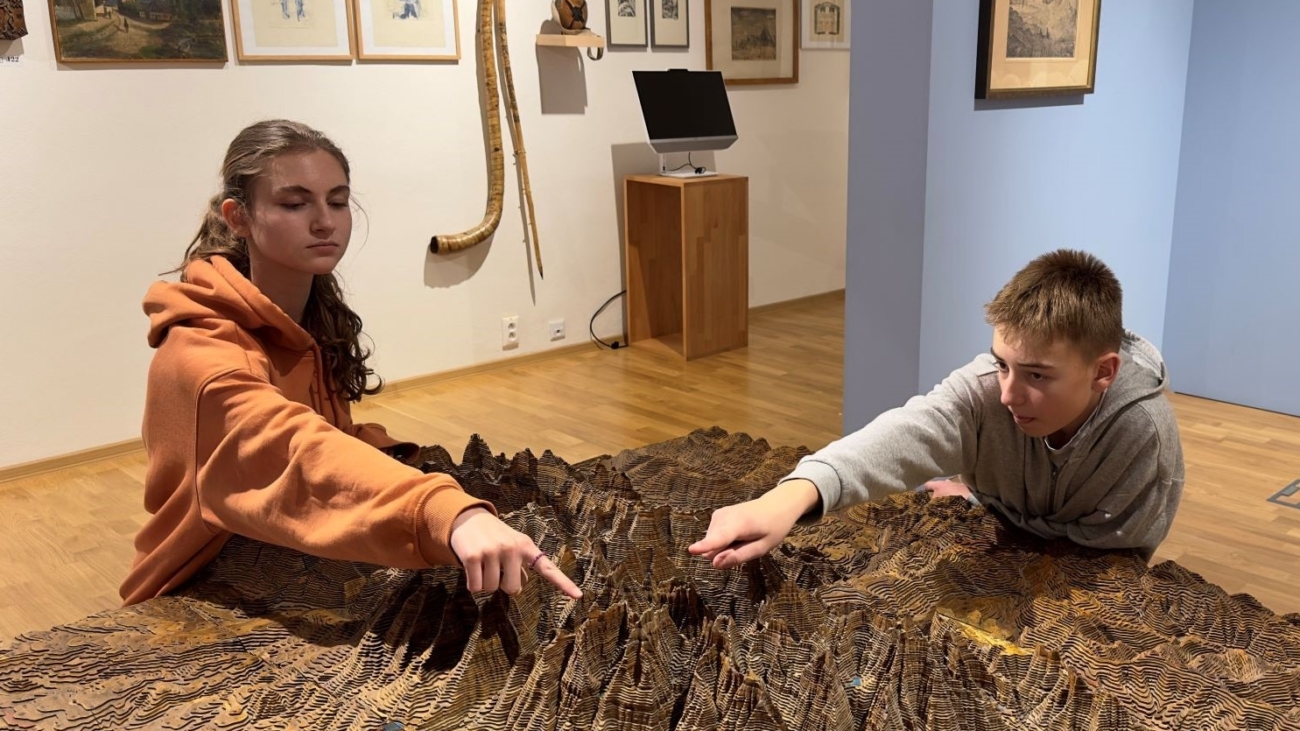 Moderátori podcastu S batohom cez hory Tánička a Vladko pri storočnej drevenej mape