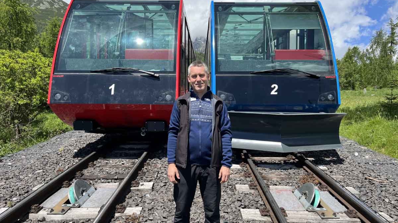 Peter Zemčák pred vozňami pozemnej lanovky v Tatrách.